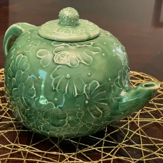 A ceramic teapot with a textured floral design